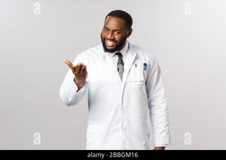 Enchanté de vous rencontrer, dites-moi votre problème. Portrait de médecin afro-américain poli et amical et charismatique invitant le patient à s'asseoir et à expliquer Banque D'Images