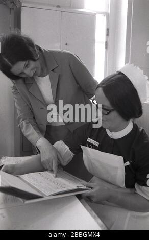 Années 1970, historique, une femme médecin avec infirmière sœur regardant les notes médicales d'un patient, Lewisham, South East London, Angleterre, Royaume-Uni. Banque D'Images