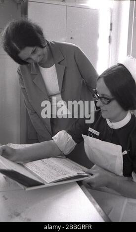 Années 1970, historique, une femme médecin avec infirmière sœur regardant les notes médicales d'un patient, Lewisham, South East London, Angleterre, Royaume-Uni. Banque D'Images