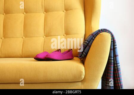 Pantoufles et couverture violettes sur un autocar jaune. Encore des détails de la vie dans la maison intérieure du salon. Intérieur confortable, concept de confort à la maison, sexe Banque D'Images