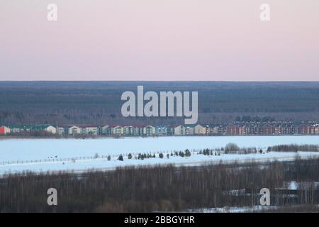 Paysage d'hiver avec une ligne de maisons de campagne en toile de fond du ciel coucher du soleil et du massif forestier. Stocker la photo pour eb et imprimer avec un espace vide pour le texte et le dégn Banque D'Images