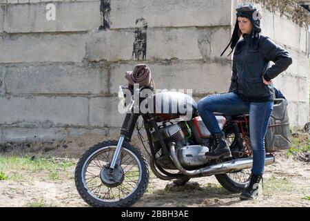 Une femme post apocalyptique près de la moto près de la construction détruite Banque D'Images