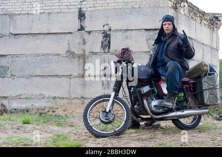 Un post apocalyptique homme sur la moto près de la construction détruite Banque D'Images