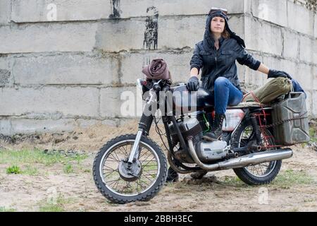Une femme post apocalyptique sur moto près d'un bâtiment détruit Banque D'Images