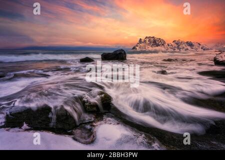 Coucher de soleil spectaculaire sur la plage, avec vagues se lavant sur les rochers côtiers Banque D'Images