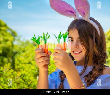 Portrait d'une jolie petite fille de lapin avec des carottes dans les mains appréciant Pâques, ayant un jardinage amusant dans la cour sur une journée ensoleillée de printemps, tenue traditionnelle Banque D'Images