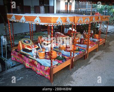 Lits ornementaux et élaborés, alignés dans une rue de Luang Prabang, au Laos. Chacun est un cadeau à un jeune homme sur le point de rejoindre un monastère bouddhiste. Le moine reçoit une variété d'articles dont il pourrait avoir besoin - un tapis de couchage, une fiole à vide, un ventilateur, un seau en plastique, un panier à riz, un oreiller, des serviettes et bien plus encore. Les billets de banque lao - Kip - sont épinglés à la voûte de chaque lit. La ville de Luang Prabang est classée au patrimoine mondial de l'UNESCO. Banque D'Images