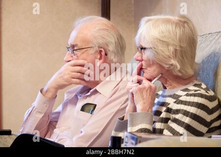 Londres, Angleterre / Royaume-Uni - 2 février 2020: Couple senior de personnes âgées regardant les nouvelles sur la télévision concernée de la propagation de Coronavirus Banque D'Images