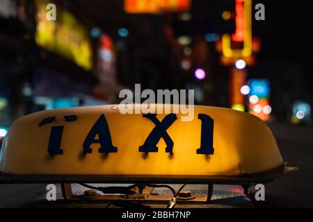 Photo nocturne d'un panneau de taxi de tuk tuk. Un vieux panneau de taxi sur le toit brille dans le noir Banque D'Images