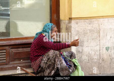 Une vieille femme mendiant dans la rue de la ville en Roumanie, en Europe Banque D'Images