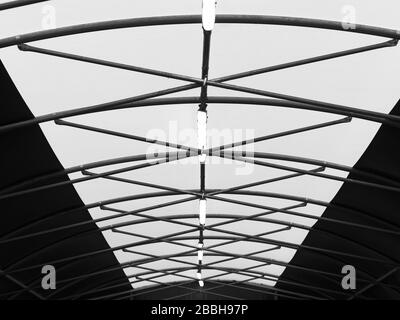 Vue de bas angle et perspective de rood voûtée avec poutres de toit en acier. Image d'architecture abstraite en noir et blanc. Banque D'Images