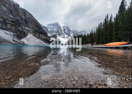 Montagnes Rocheuses avec canoë sur la jetée du lac Moraine, sur une sombre lugubre dans le parc national Banff, Canada Banque D'Images