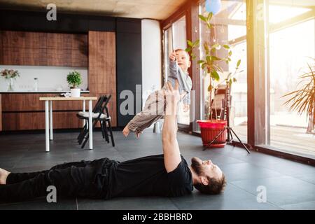 Père jouant et soulevant bébé dans l'air et faisant de l'exercice Banque D'Images