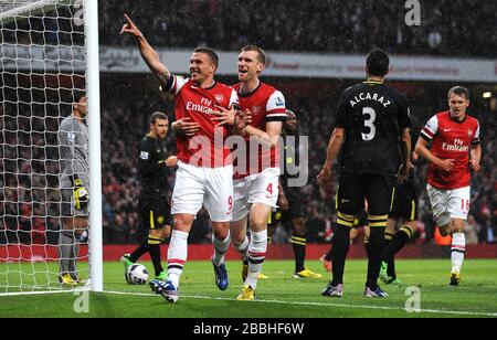 Lukas Podolski (à gauche) d'Arsenal célèbre avec Per Mertesacker (à droite) après avoir marqué le but d'ouverture du jeu contre Wigan Athletic. Banque D'Images