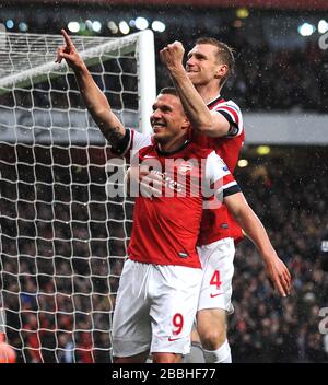 Lukas Podolski (à gauche) d'Arsenal célèbre avec Per Mertesacker (à droite) après avoir marqué le but d'ouverture du jeu contre Wigan Athletic. Banque D'Images
