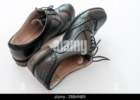 Vue en haut vers le bas d'une paire de brogues en cuir noir classique sur fond blanc Uni, avec une chaussure droite et l'autre sur son côté Banque D'Images