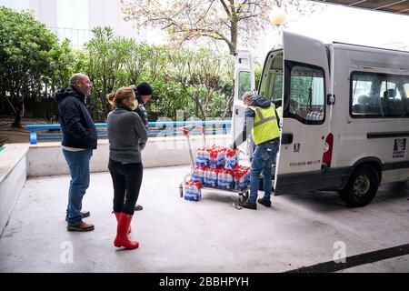 Les hommes de livraison déchargeant l'eau donnée.'Federacion de Penas' de Mostoles donne 4 000 l d'eau minérale à l'hôpital universitaire de Mostoles pour aider à lutter contre la pandémie du virus corona. Banque D'Images