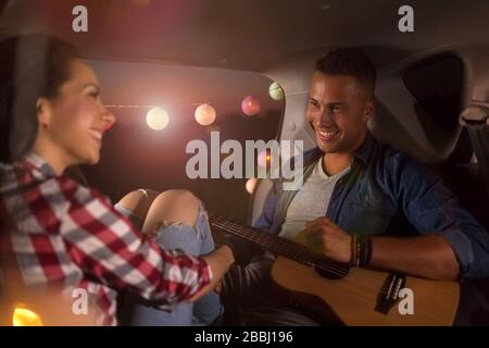 Couple amoureux assis dans un coffre de voiture et regarder le coucher du soleil Banque D'Images