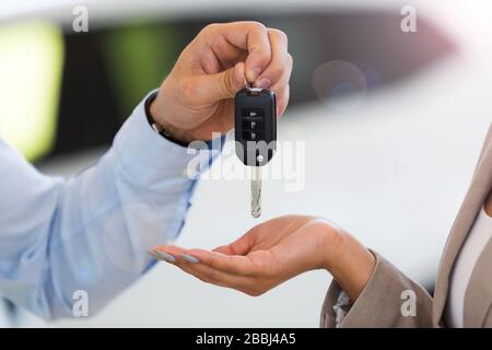 Le vendeur de voiture remettant les clés de voiture à une femme dans le hall d'exposition Banque D'Images