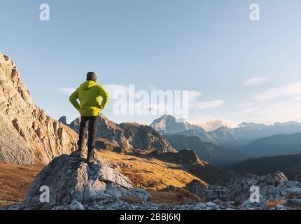 Sportif homme debout sur la pierre contre les montagnes au coucher du soleil Banque D'Images