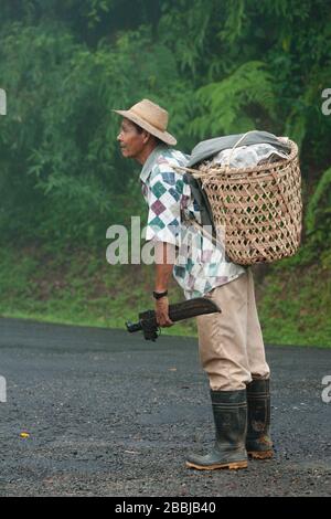 L'agriculteur panamanien marche le long de la route avec un panier à l'arrière et un couteau à la main, la province du Cercle, la forêt nuageuse du centre du Panama, en Amérique centrale Banque D'Images