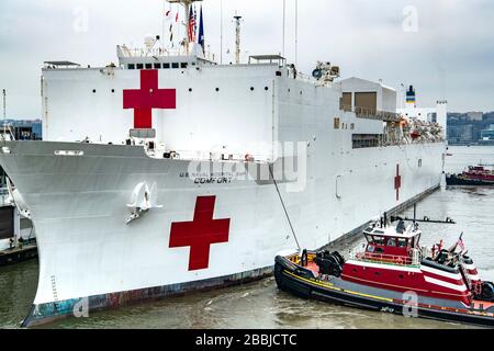 New York, États-Unis d'Amérique. 31 mars 2020. Le navire hospitalier US Navy Military Seallift Command USNS Comfort est poussé dans le quai de l'embarcadère 90 par des remorqueurs après son arrivée dans le port de New York le 31 mars 2020 à New York City, New York. Le Comfort se déploie dans la ville pour appuyer les efforts de réponse du COVID-19 du pays. Crédit: Kenneth Wilsey/FEMA/Alay Live News Banque D'Images