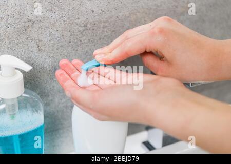 Les mains des femmes prennent du savon gel pour se laver les mains à la maison salle de bain laver le robinet et l'évier pour protéger la peau contre les virus et les microbes pendant l'épidième du coronavirus Banque D'Images