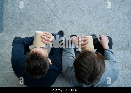 Vue de dessus de deux jeunes hommes assis sur un escalier de la ville et un pof Banque D'Images