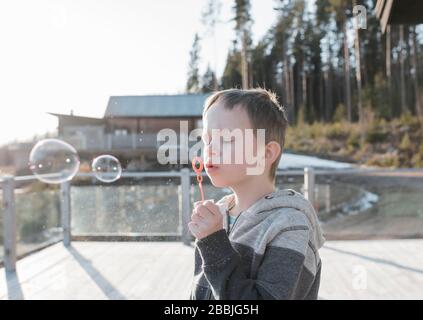 Garçon soufflant des bulles sur son balcon à la maison en Suède Banque D'Images