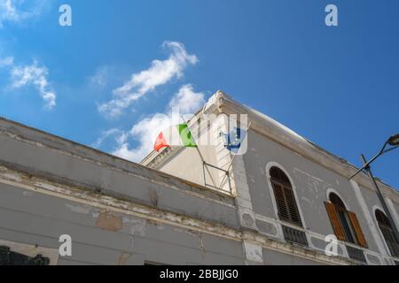 Un drapeau italien et un drapeau déchiré de l'Union européenne survolent un bâtiment usé à Brindisi Italie dans la région des Pouilles. Banque D'Images