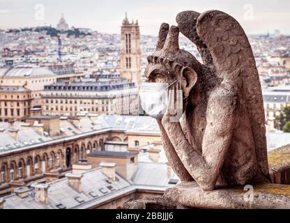 COVID-19 coronavirus en France, masque médical sur gargoyle de notre Dame à Paris. Les sites touristiques fermés en raison de l'épidémie de virus corona. Concept de tra Banque D'Images