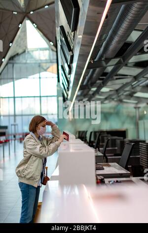 Femme avec bagages sur annulation de vol, se tient aux comptoirs d'enregistrement vides au terminal de l'aéroport en raison de la pandémie de coronavirus/éclosion de Vivid-19 trave Banque D'Images