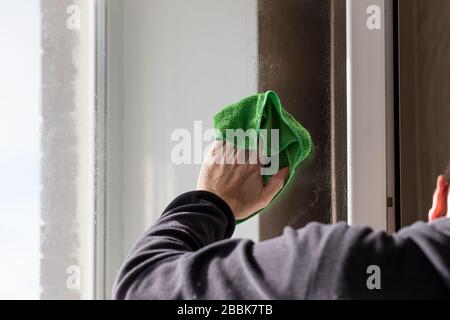 Nettoyage des fenêtres avec un chiffon spécial et plus propre, les mains mâles lave la vitre de fenêtre dans la maison d'appartement. Nettoyage de la fenêtre.nettoyage de la maison. Fenêtre sale de lavage Banque D'Images