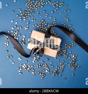 Cire à grains de perle noire pour l'épilation sur fond bleu classique avec boîte cadeau. Espace de copie, bannière, prospectus, texture minimale du coupon. Le concept de promotion Banque D'Images