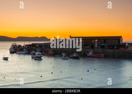 Lyme Regis, Dorset, Royaume-Uni. 1 avril 2020. Météo britannique. Le ciel clair brille en orange au-dessus du port de Cobb au lever du soleil à Lyme Regis à Dorset. Crédit photo : Graham Hunt/Alay Live News Banque D'Images
