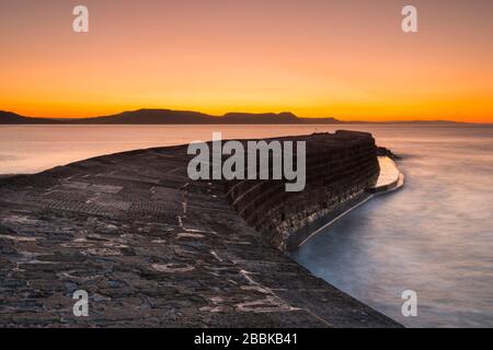 Lyme Regis, Dorset, Royaume-Uni. 1 avril 2020. Météo britannique. Le ciel clair brille en orange au-dessus du port de Cobb au lever du soleil à Lyme Regis à Dorset. Crédit photo : Graham Hunt/Alay Live News Banque D'Images