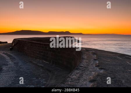 Lyme Regis, Dorset, Royaume-Uni. 1 avril 2020. Météo britannique. Le ciel clair brille en orange au-dessus du port de Cobb au lever du soleil à Lyme Regis à Dorset. Crédit photo : Graham Hunt/Alay Live News Banque D'Images