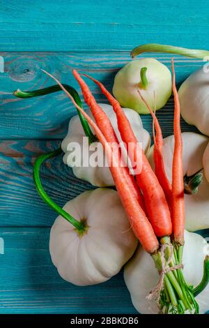 Ensemble de légumes : les carottes, les pâtisseries aux queues vertes et les courgettes multicolores se trouvent sur une vieille table en bois Banque D'Images