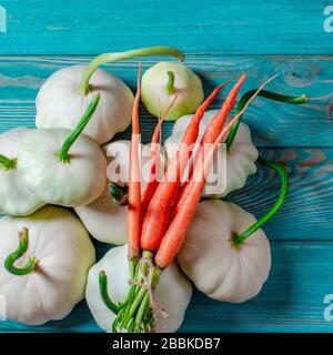 Ensemble de légumes : les carottes, les pâtisseries aux queues vertes et les courgettes multicolores se trouvent sur une vieille table en bois Banque D'Images