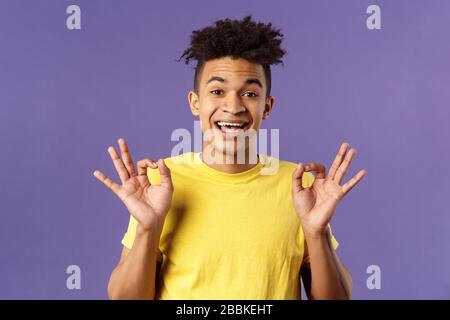 Gros plan portrait de jeune homme chic et détendu avec des bandes de roulement assurant tout le bien, tout est OK, montrer bon geste et sourire, pas de problème Banque D'Images