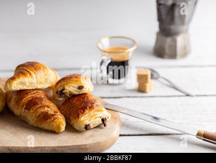 Petit-déjeuner avec croissants, petits pains à la cannelle et biscuits au chocolat, jus d'orange frais et café sur le côté sur fond blanc. Banque D'Images