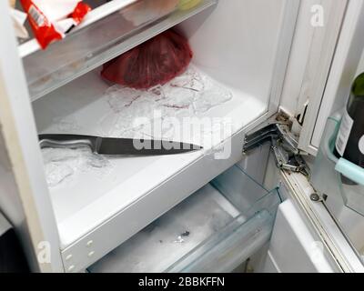 Retirer la glace d'un congélateur avec couteau de cuisine, fermeture intérieure Banque D'Images