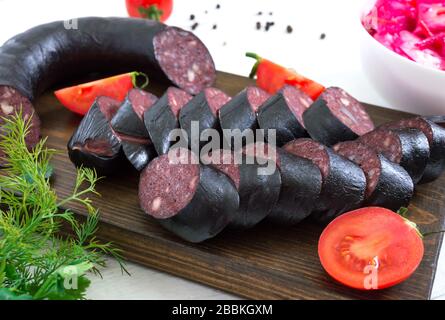 Morsilla - saucisse de sang. Morceaux de pouding noir espagnol sur un tableau de découpe en bois sur fond blanc. Menu de Pâques. Banque D'Images