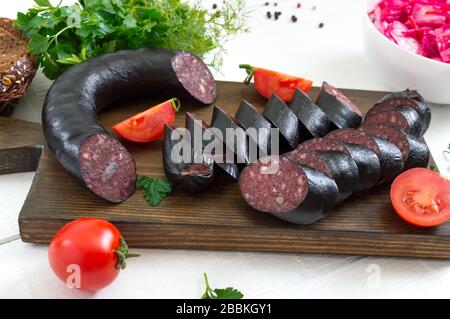 Morsilla - saucisse de sang. Morceaux de pouding noir espagnol sur un tableau de découpe en bois sur fond blanc. Menu de Pâques. Banque D'Images