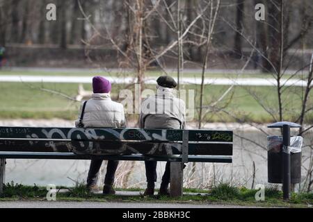 Munich, Allemagne. 01 avril 2020. Un retraité et une femme s'assoient sur un banc sur les rives de l'Isar à Muenchen-Lehel. | utilisation dans le monde crédit: dpa/Alay Live News Banque D'Images