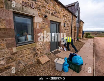 East Lothian, Écosse, Royaume-Uni. 1 avril 2020. Livraisons locales de nourriture pendant la pandémie de Coronavirus de Covid-19: Yester Farm Dairies commence deux fois par semaine des livraisons gratuites de maison aux résidents de East Lothian. Yester secteur est une ferme familiale qui fournit des produits laitiers artisanaux primés. Ils ont été inondés de commandes. Photo: Dale, qui fait normalement du fromage à la laiterie fait une livraison à la maison de lait et de yaourts à une famille qui sont auto-isolation Banque D'Images