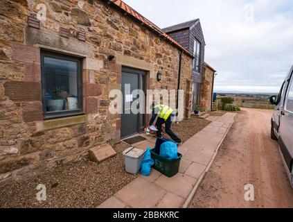 East Lothian, Écosse, Royaume-Uni. 1 avril 2020. Livraisons locales de nourriture pendant la pandémie de Coronavirus de Covid-19: Yester Farm Dairies commence deux fois par semaine des livraisons gratuites de maison aux résidents de East Lothian. Yester secteur est une ferme familiale qui fournit des produits laitiers artisanaux primés. Ils ont été inondés de commandes. Photo: Dale, qui fait normalement du fromage à la laiterie fait une livraison à la maison de lait et de yaourts à une famille qui sont auto-isolation Banque D'Images