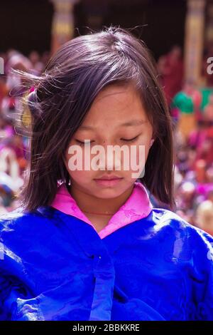 Portrait d'une jeune fille timide portant le costume traditionnel de Kira (robe), et la veste extérieure bleue (Tego) au Thimphu Tshechu Festival, Bhoutan Banque D'Images