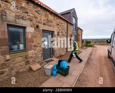 East Lothian, Écosse, Royaume-Uni. 1 avril 2020. Livraisons locales de nourriture pendant la pandémie de Coronavirus de Covid-19: Yester Farm Dairies commence deux fois par semaine des livraisons gratuites de maison aux résidents de East Lothian. Yester secteur est une ferme familiale qui fournit des produits laitiers artisanaux primés. Ils ont été inondés de commandes. Photo: Dale, qui fait normalement du fromage à la laiterie fait une livraison à la maison de lait et de yaourts à une famille qui sont auto-isolation Banque D'Images