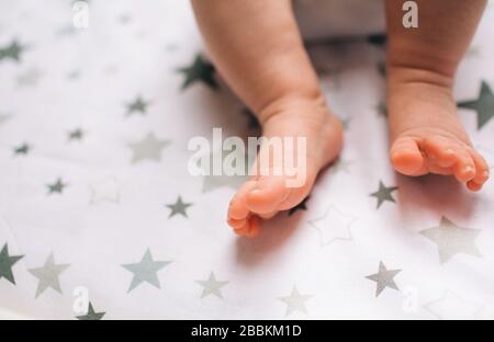 Pieds gros plan d'un nouveau-né. Le petit bébé est allongé sur la table pour enfants . Il y a un enfant de nouveau-né sur la table de changement de bébé près de la fenêtre. Banque D'Images